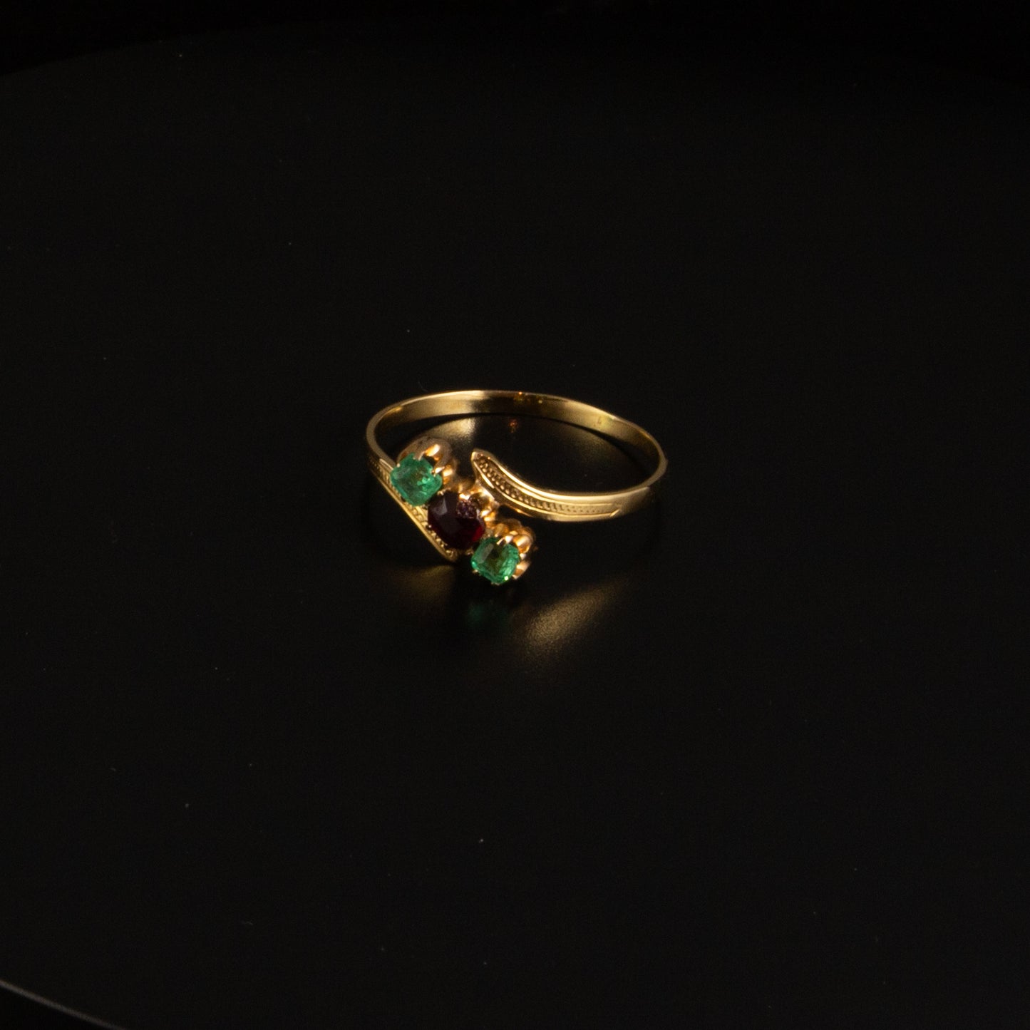Anillo oro y piedras verdes y rojas.
