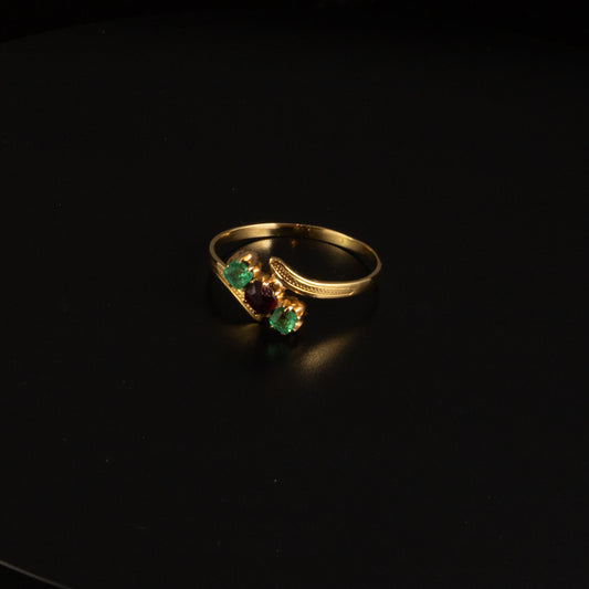 Anillo oro y piedras verdes y rojas.